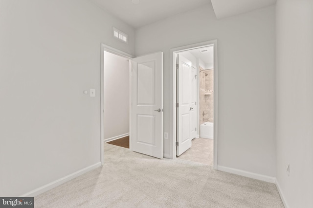 interior space featuring ensuite bath and light carpet