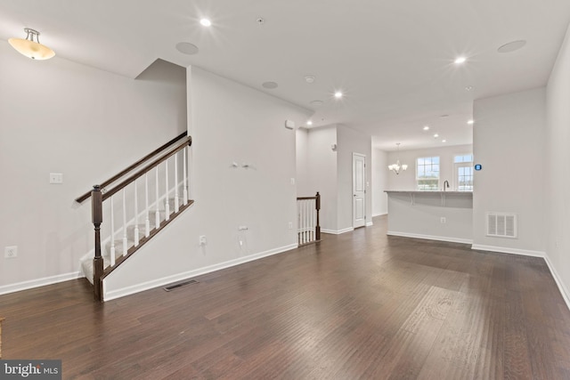 unfurnished living room with an inviting chandelier, sink, and dark wood-type flooring