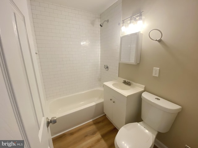 full bathroom featuring vanity, hardwood / wood-style flooring, tiled shower / bath combo, and toilet