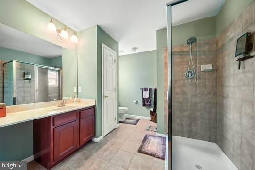 bathroom with tile patterned floors, vanity, toilet, and a shower with shower door