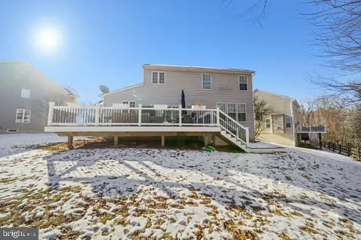 snow covered back of property featuring a wooden deck