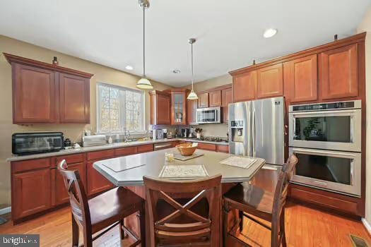 kitchen with a kitchen island, appliances with stainless steel finishes, a breakfast bar area, and decorative light fixtures