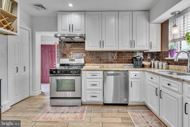 kitchen with sink, decorative light fixtures, stainless steel range with gas stovetop, light stone countertops, and white cabinets