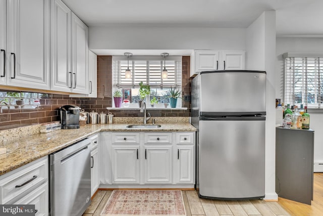 kitchen with white cabinetry, sink, stainless steel appliances, and hanging light fixtures