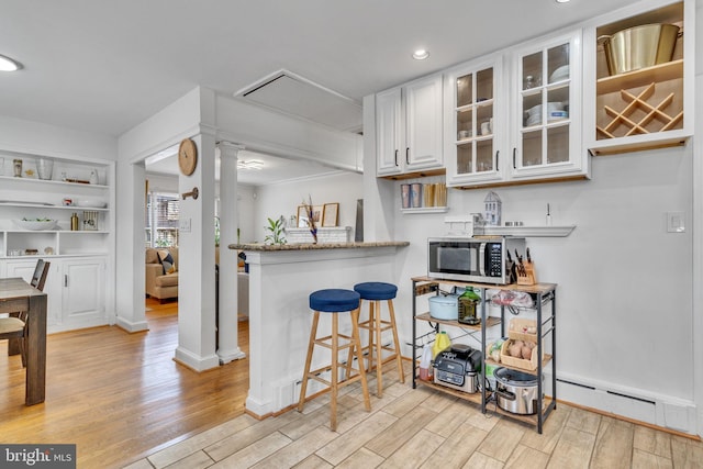 kitchen featuring ornate columns, white cabinetry, a baseboard radiator, and light hardwood / wood-style flooring