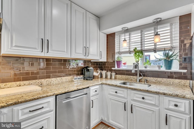 kitchen with hanging light fixtures, sink, stainless steel dishwasher, and white cabinets