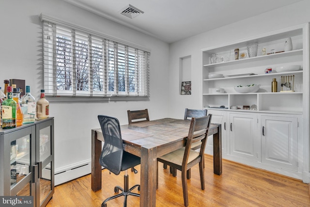 dining room featuring a baseboard heating unit and light wood-type flooring