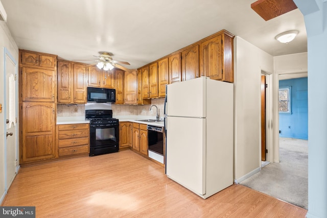 kitchen with sink, decorative backsplash, ceiling fan, black appliances, and light hardwood / wood-style flooring