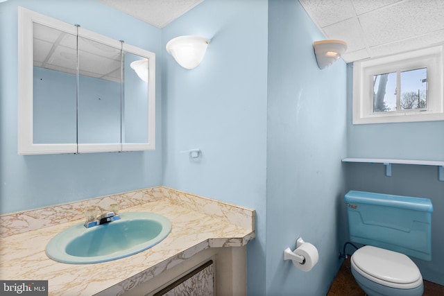 bathroom featuring vanity, a drop ceiling, and toilet