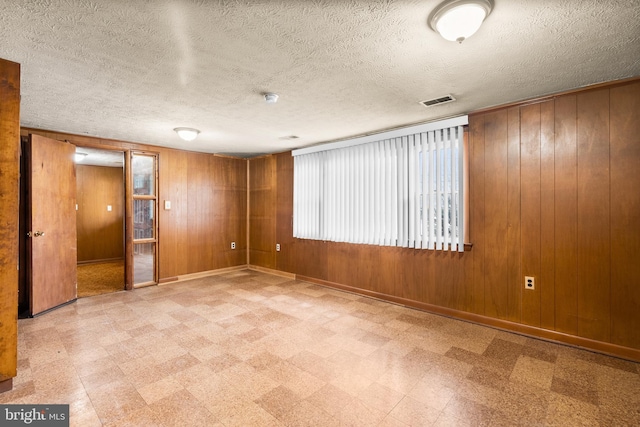 unfurnished room featuring wooden walls and a textured ceiling