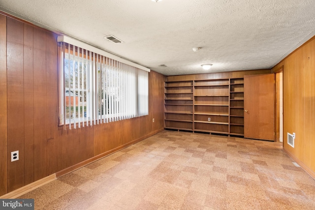 spare room with a textured ceiling and wood walls