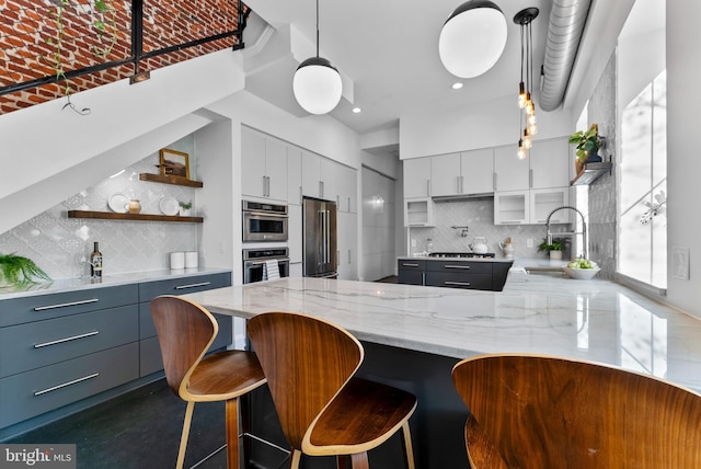 kitchen featuring appliances with stainless steel finishes, a kitchen breakfast bar, light stone countertops, and white cabinets