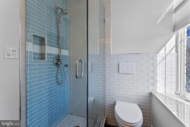 bathroom with tile walls, an enclosed shower, and toilet