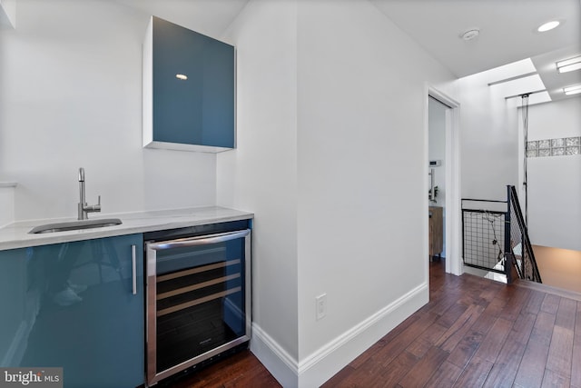 bar with blue cabinetry, sink, wine cooler, and dark hardwood / wood-style floors