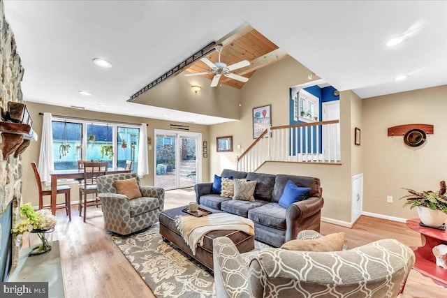 living room featuring a stone fireplace, vaulted ceiling, ceiling fan, and light wood-type flooring