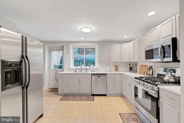 kitchen featuring light tile patterned flooring, sink, tasteful backsplash, appliances with stainless steel finishes, and white cabinets