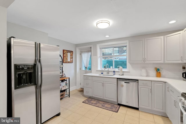 kitchen featuring sink, white cabinets, decorative backsplash, light tile patterned floors, and stainless steel appliances