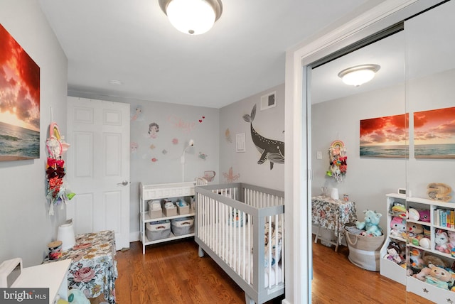 bedroom featuring a crib and dark wood-type flooring