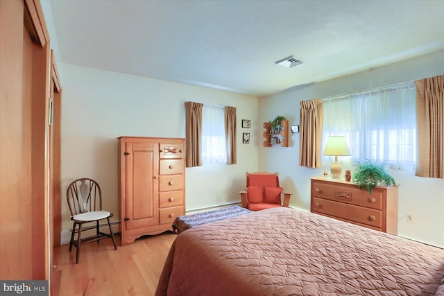 bedroom with baseboard heating and light hardwood / wood-style flooring