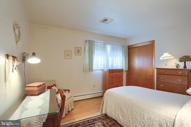 bedroom featuring wood-type flooring, a closet, and a baseboard heating unit