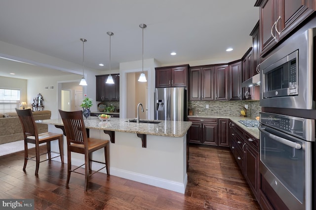 kitchen featuring a breakfast bar, pendant lighting, sink, a kitchen island with sink, and stainless steel appliances