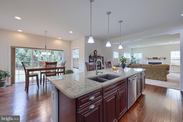 kitchen with pendant lighting, sink, a kitchen island with sink, dark hardwood / wood-style floors, and stainless steel dishwasher