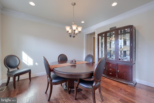 dining area featuring an inviting chandelier, hardwood / wood-style floors, and ornamental molding