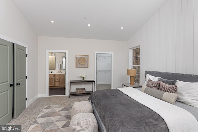 bedroom with a walk in closet, recessed lighting, a closet, light carpet, and baseboards