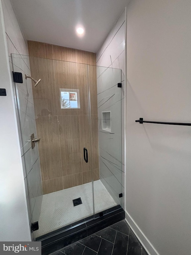 bathroom featuring a shower stall and baseboards