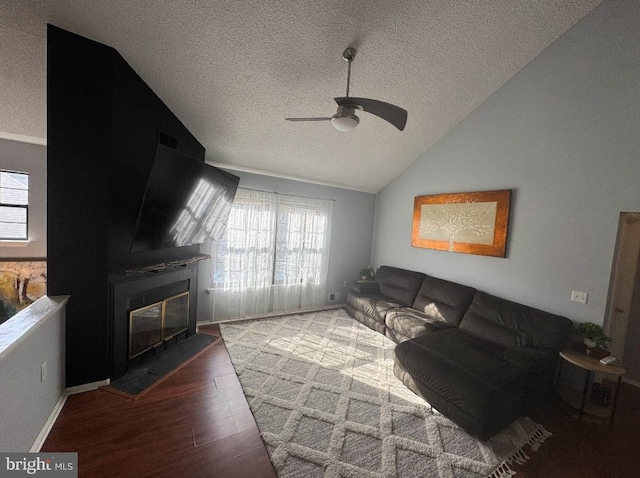 living room featuring hardwood / wood-style flooring, vaulted ceiling, a textured ceiling, and ceiling fan