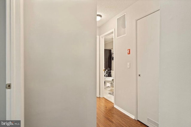 corridor featuring hardwood / wood-style floors and a textured ceiling