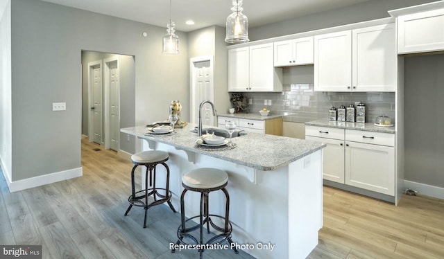 kitchen featuring sink, white cabinets, and a center island with sink