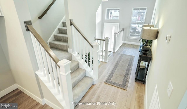 stairs with hardwood / wood-style flooring and a towering ceiling