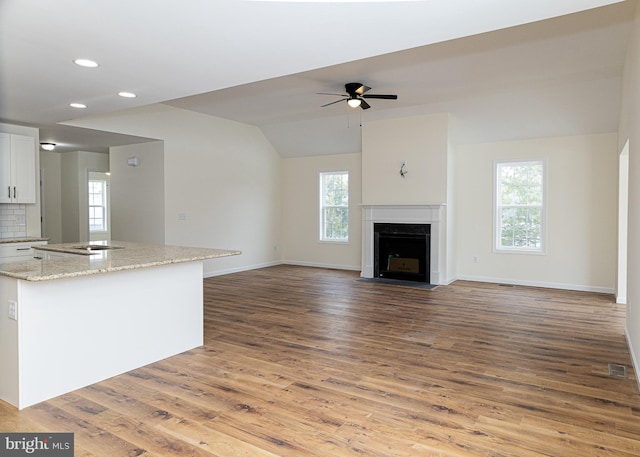 unfurnished living room with lofted ceiling, hardwood / wood-style floors, and ceiling fan