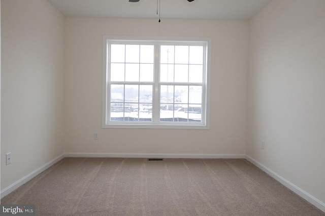 carpeted spare room featuring plenty of natural light and ceiling fan