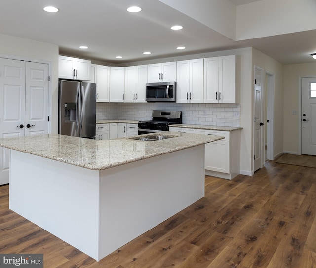 kitchen featuring white cabinetry, appliances with stainless steel finishes, and an island with sink