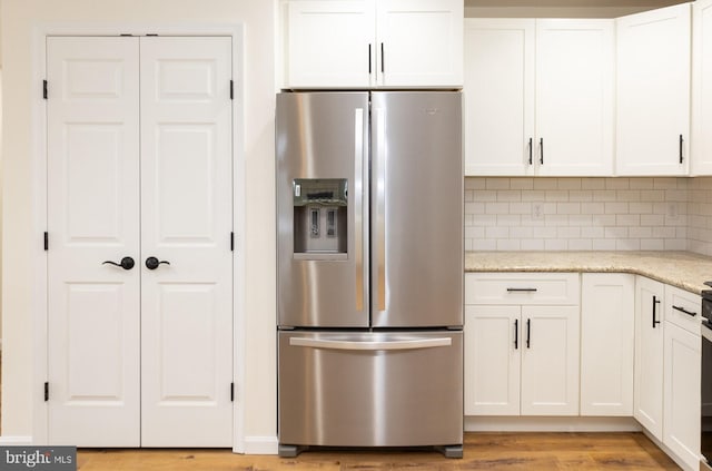 kitchen featuring white cabinetry, light stone countertops, stainless steel fridge with ice dispenser, and decorative backsplash