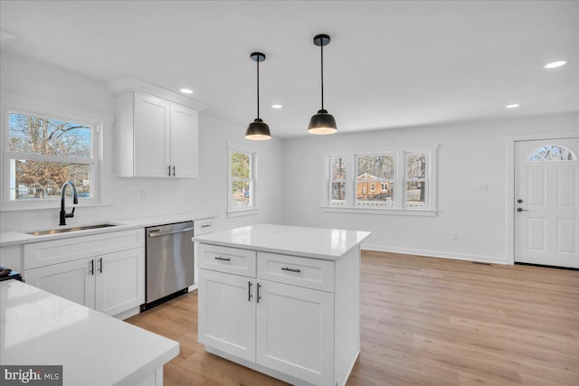 kitchen featuring sink, dishwasher, a kitchen island, pendant lighting, and white cabinets