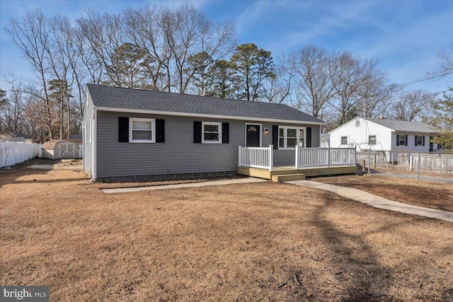 ranch-style home with a front yard, a deck, and a shed