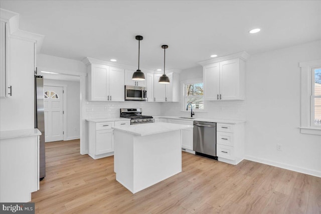 kitchen with appliances with stainless steel finishes, a center island, sink, and white cabinets