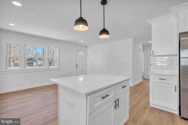 kitchen with pendant lighting, light hardwood / wood-style floors, stainless steel refrigerator, and white cabinets