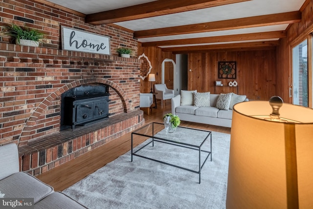 living room with beamed ceiling, wooden walls, and hardwood / wood-style floors