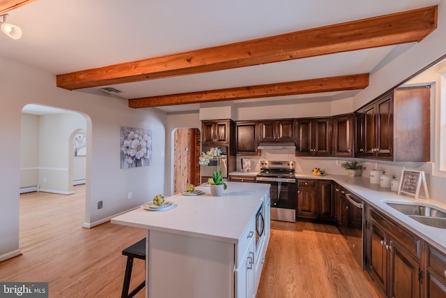 kitchen with sink, appliances with stainless steel finishes, beam ceiling, a center island, and light hardwood / wood-style floors