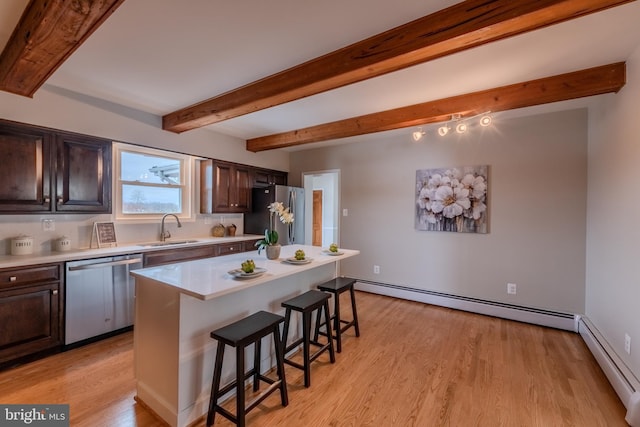 kitchen featuring a kitchen bar, sink, a baseboard radiator, a kitchen island, and stainless steel appliances