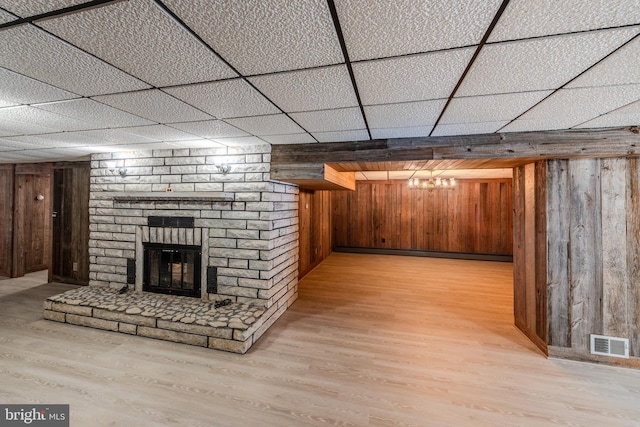 interior space with a brick fireplace, light hardwood / wood-style floors, baseboard heating, and wood walls