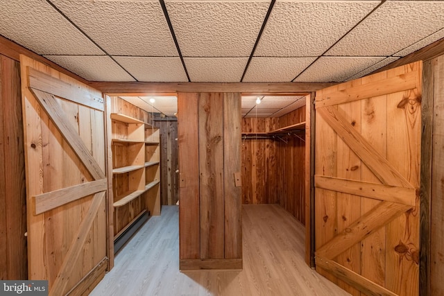 interior space with a paneled ceiling, wooden walls, and hardwood / wood-style floors