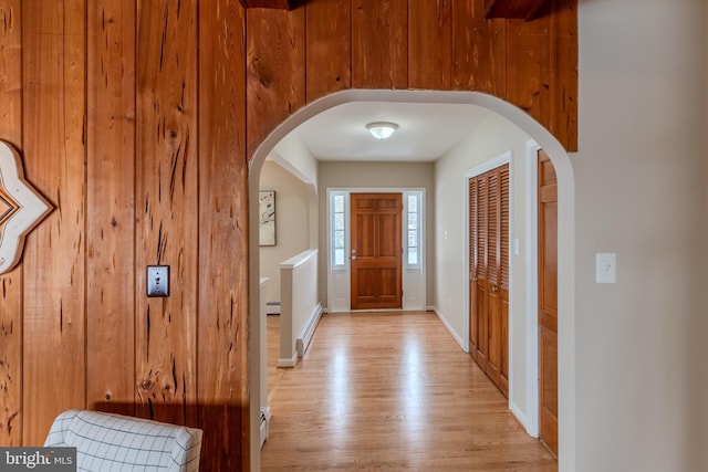 entrance foyer with a baseboard radiator, wooden walls, and light hardwood / wood-style floors