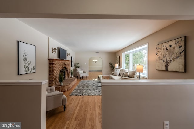 living room with a notable chandelier, a fireplace, and light hardwood / wood-style floors