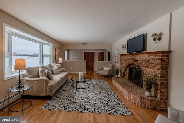 living room with hardwood / wood-style floors, a brick fireplace, and a baseboard heating unit