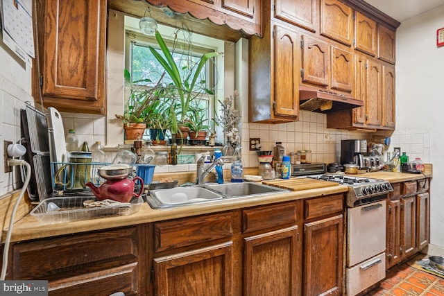 kitchen featuring sink, tile patterned flooring, white gas stove, and backsplash